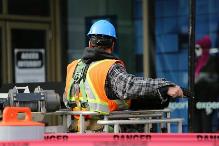 The Electrical-First Strategy: image of a man raising himself up on in a bucket on a construction site.