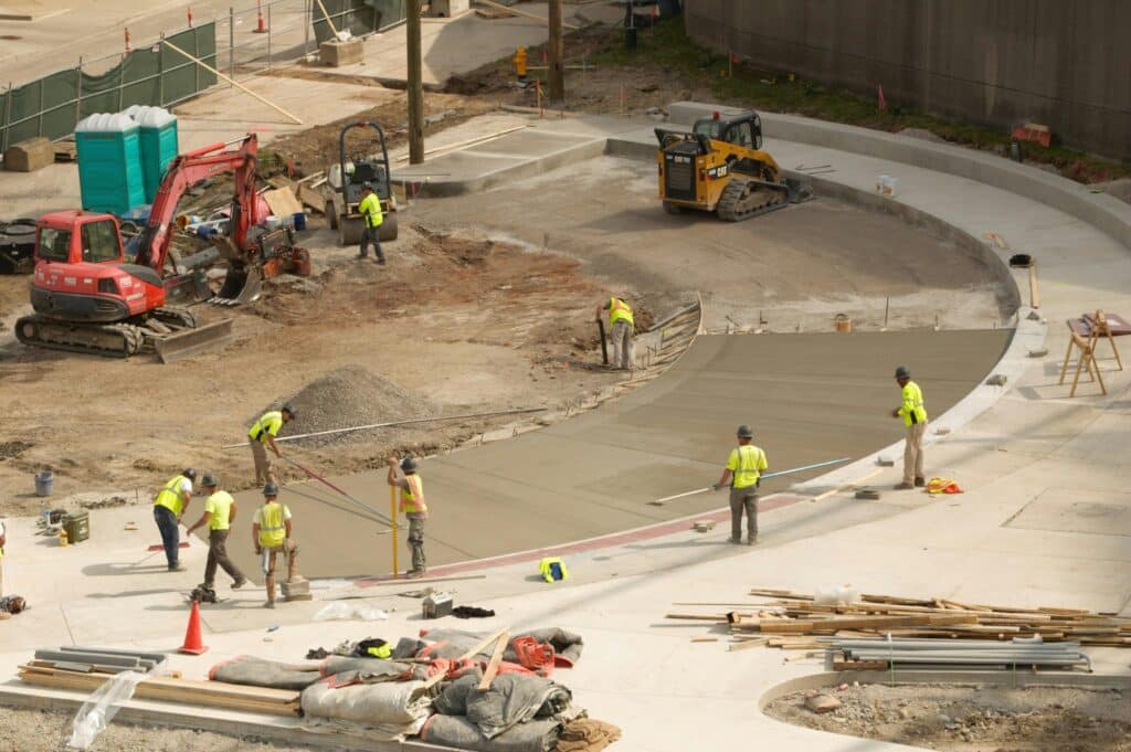 Overhead view of construction workers finishing driveway turnaround work as the project remains on schedule.