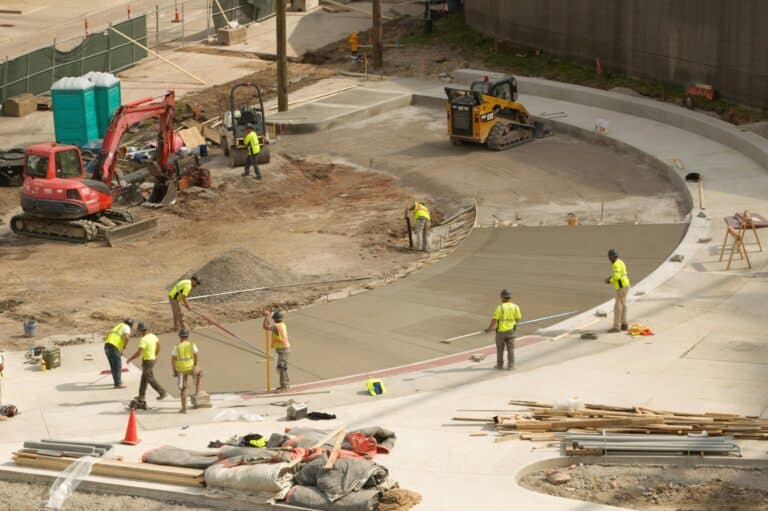 Overhead view of construction workers finishing driveway turnaround work as the project remains on schedule.